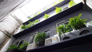 Un immeuble doté de nombreux balcons, chacun orné de plantes en pot et équipé de climatiseurs.