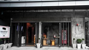 Une entrée moderne avec des portes en verre, un panneau indicateur et des plantes en pot.