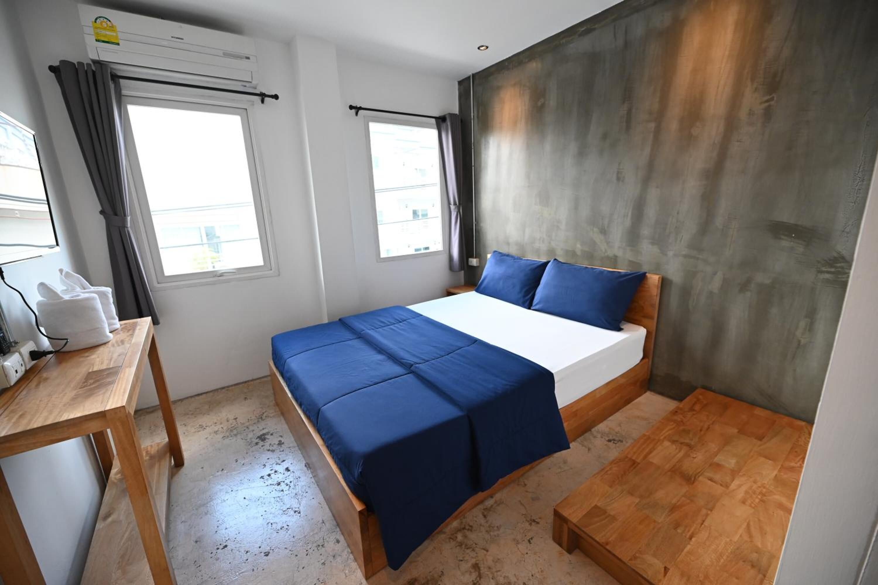 Un dormitorio con una cama, una mesa de madera y un ventanal con cortinas.