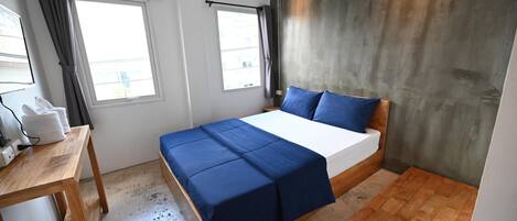 Un dormitorio con una cama, una mesa de madera y un ventanal con cortinas.