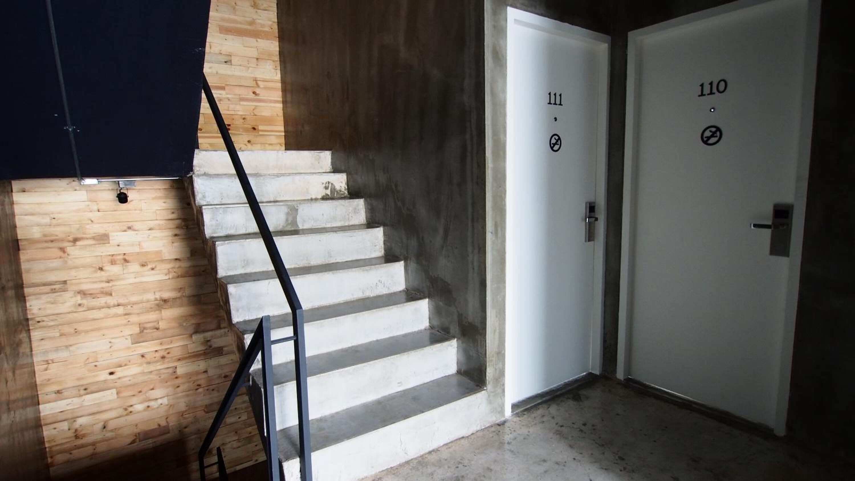 A staircase with a metal handrail leading to a door marked with the number 111.