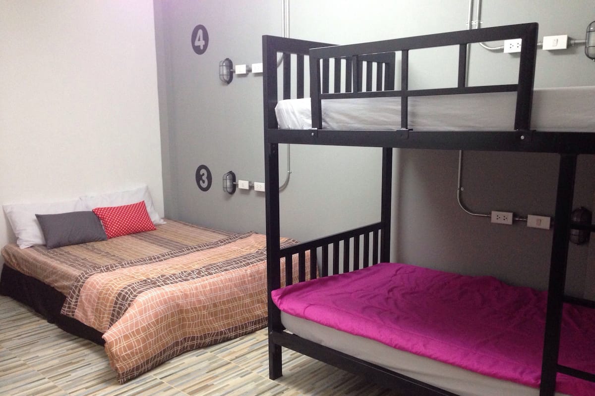 Two bunk beds in a room with a striped floor, a wall-mounted light, and a number indicating room 4.
