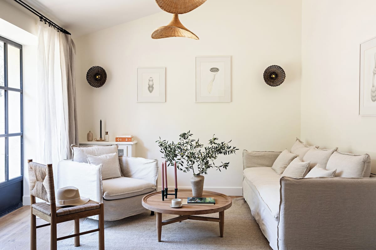 Un salon comprenant un canapé, des fauteuils, une table basse, une plante et des œuvres d’art mural.