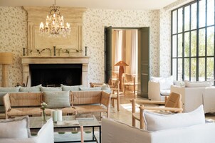 A spacious living room with a fireplace, a chandelier, and a large window.