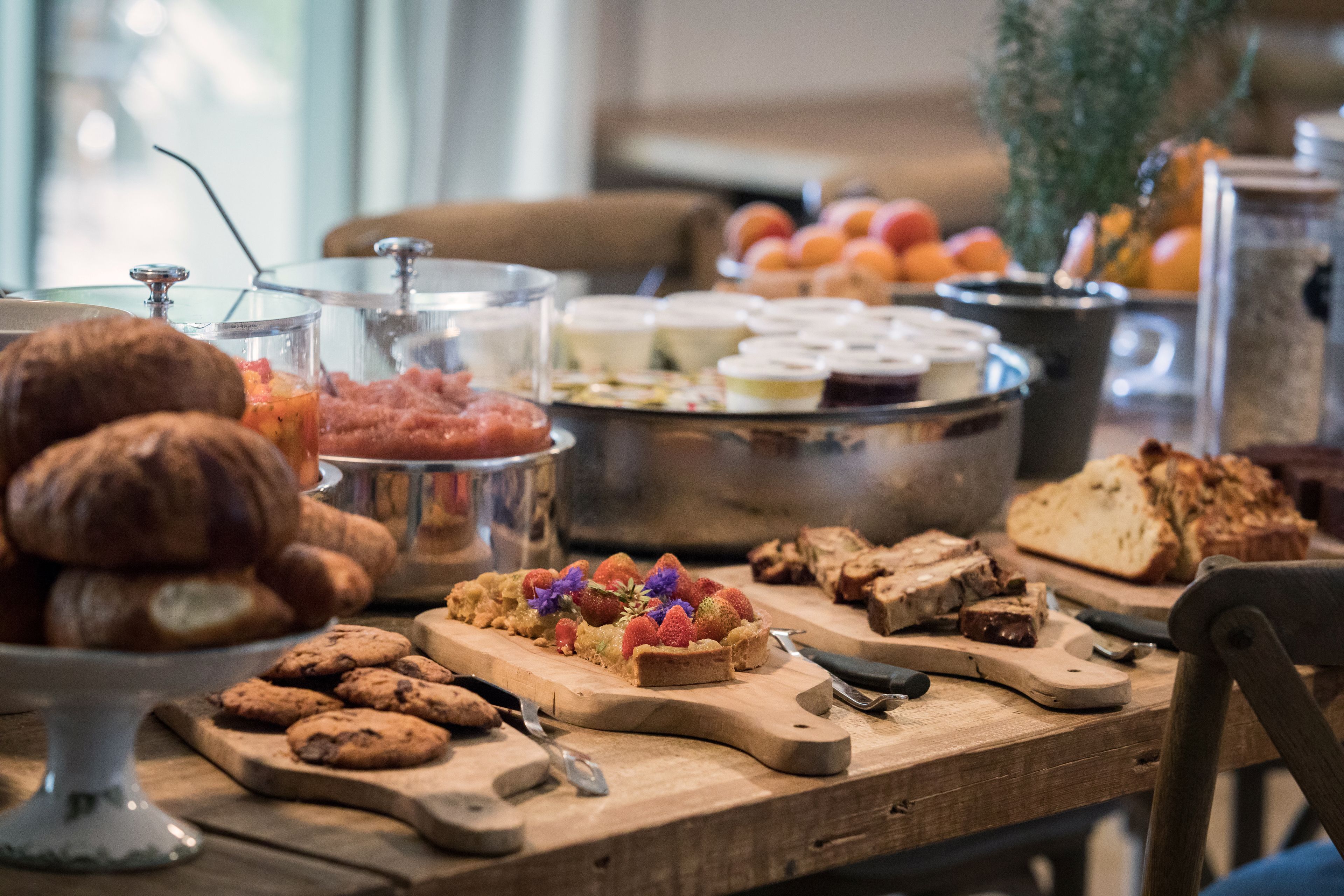 A breakfast buffet with various pastries, fruits, and bread.