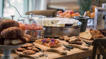 A breakfast buffet with various pastries, fruits, and bread.