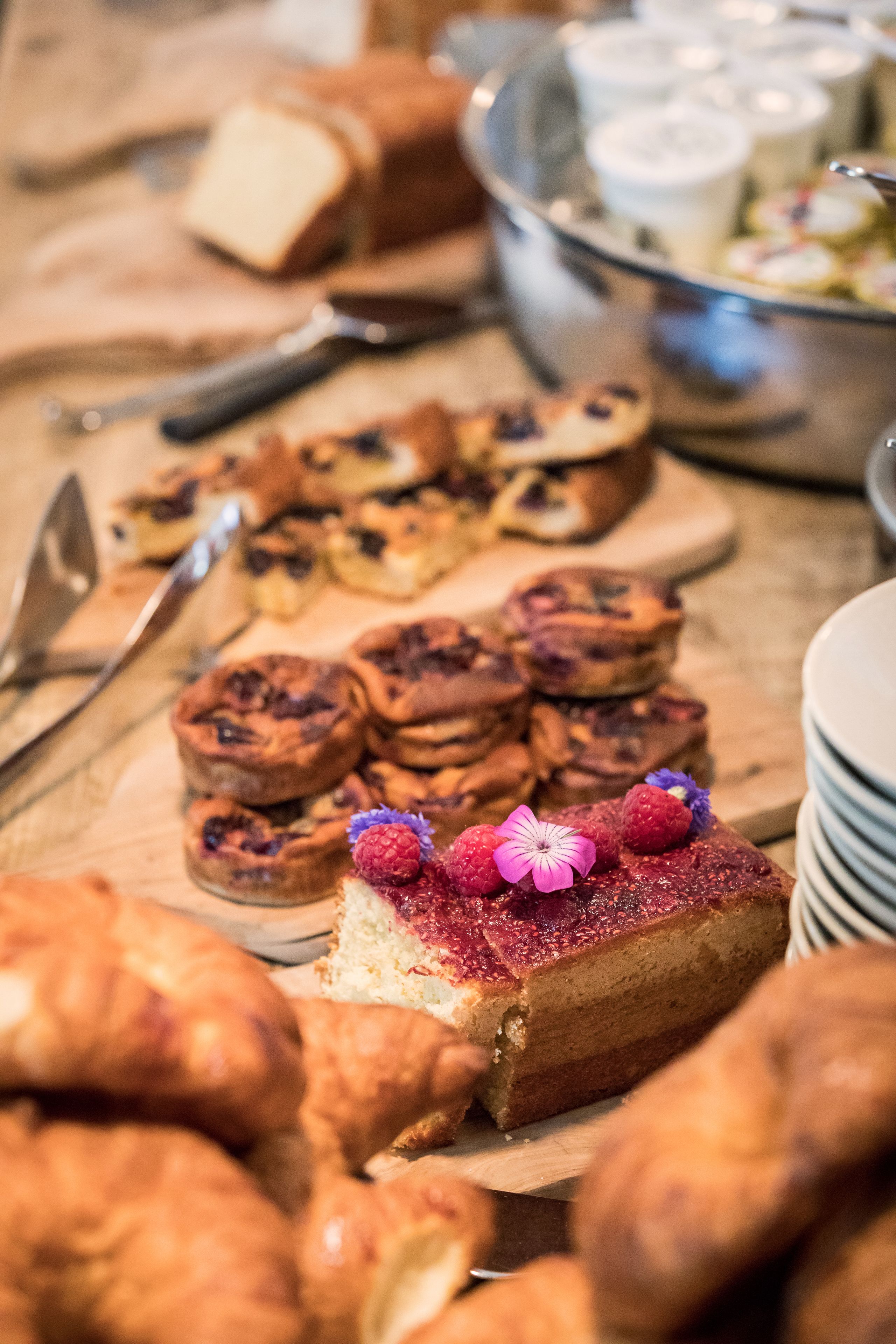 Une variété de produits de boulangerie, notamment des pâtisseries et une part de gâteau décorée de fruits rouges et d’une fleur.