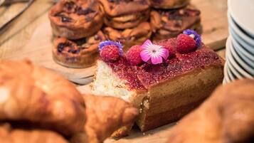 Une variété de produits de boulangerie, notamment des pâtisseries et une part de gâteau décorée de fruits rouges et d’une fleur.