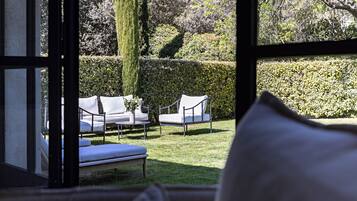 Een kamer met uitzicht op een tuin, met een bank en een zitje.