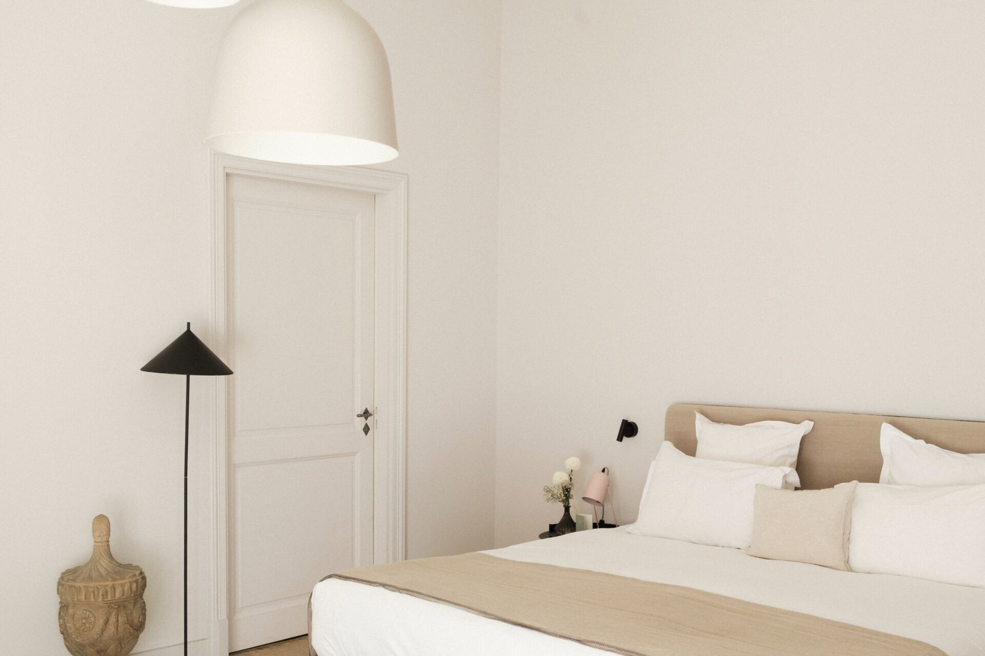 Un dormitorio con cama, mesita de noche, lámpara y una puerta.