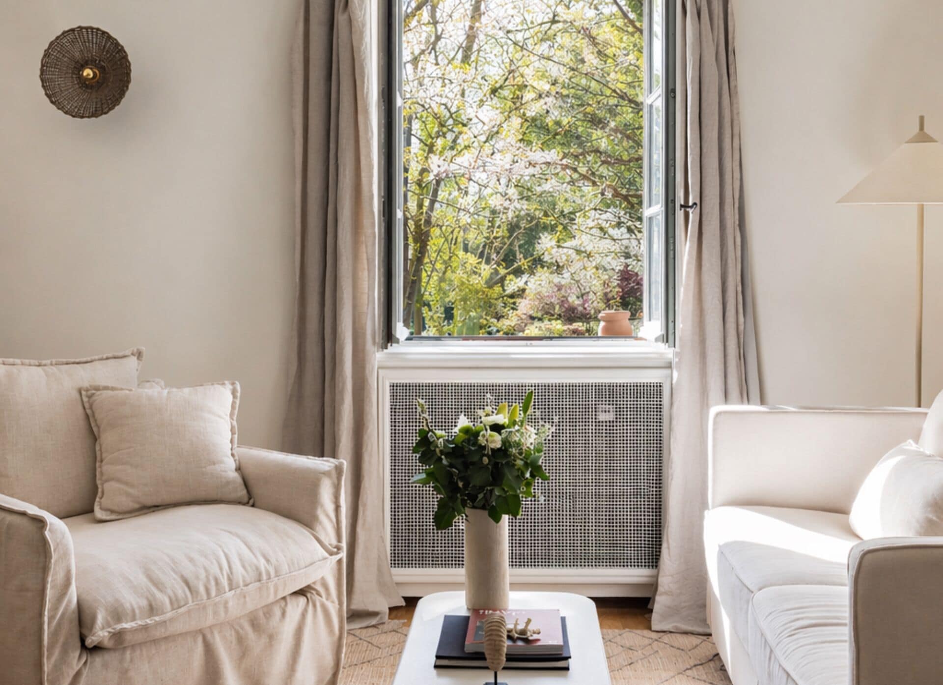 A room with a white sofa, a small table with a plant, and a window with curtains.
