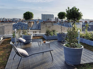 En tagterrasse med siddepladser, plantekasser og udsigt over bybilledet.