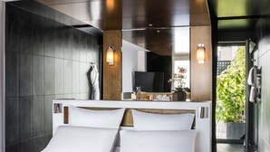 Moderni hotellihuone, jossa on suuri sänky, televisio sekä kylpyhuone, jossa on suihku ja wc.