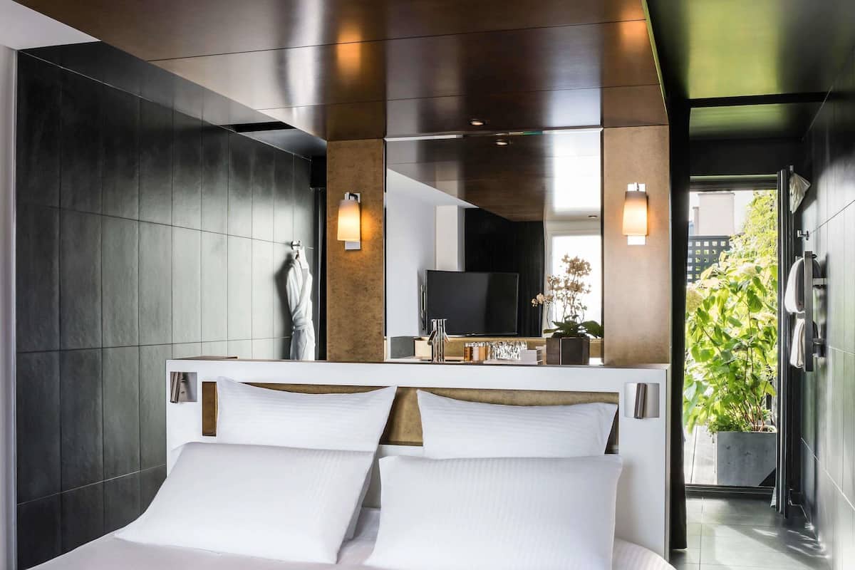 A modern hotel room with a large bed, a TV, and a bathroom with a shower and toilet.