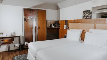 Habitación de hotel con cama, escritorio, silla, armario y una pequeña cocina.