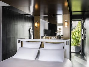 Et moderne hotelværelse med en stor seng, fjernsyn, badeværelse og udsigt til grønne områder.