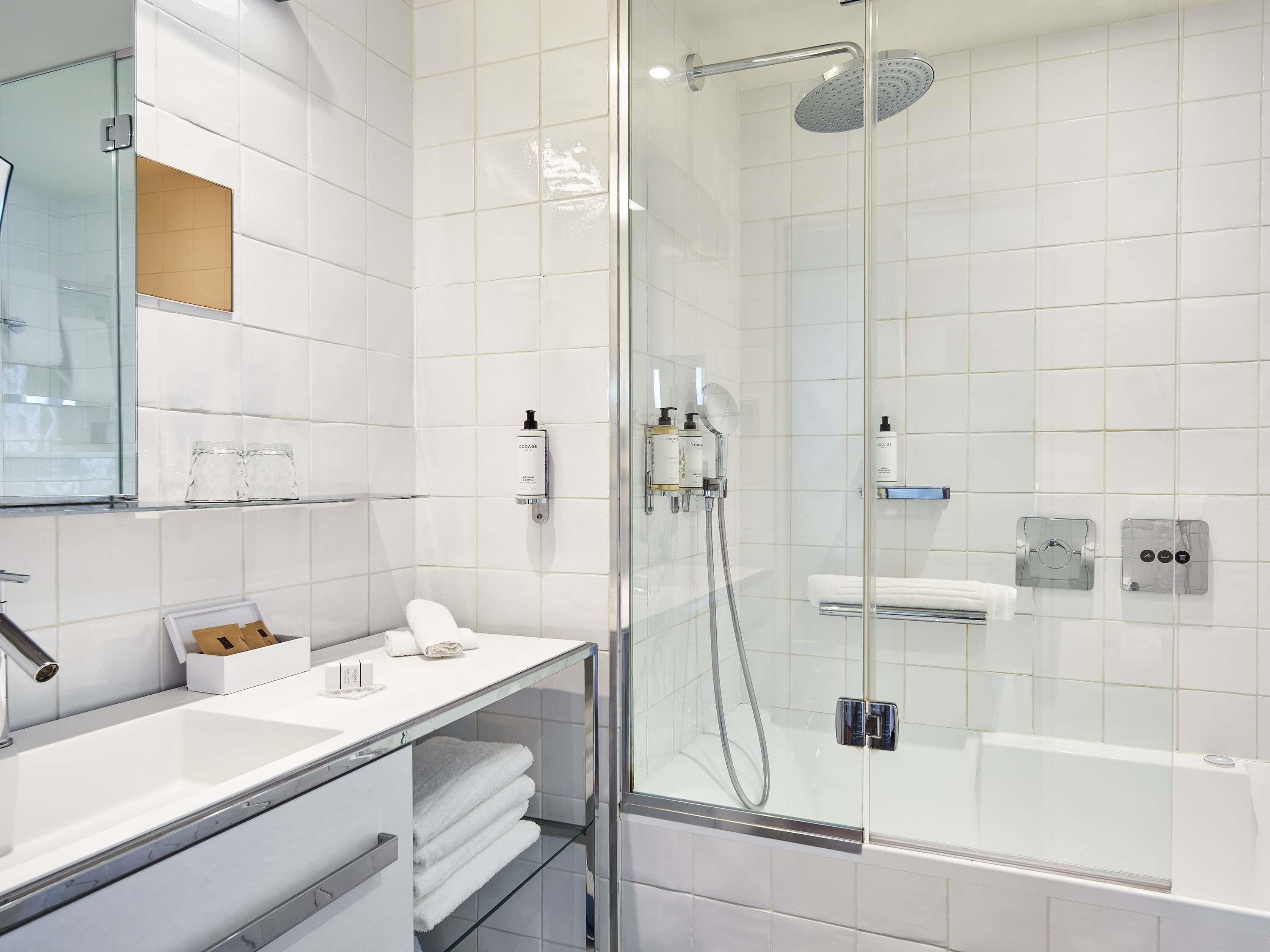 Un baño moderno con ducha de vidrio, lavamanos blanco y espejo.