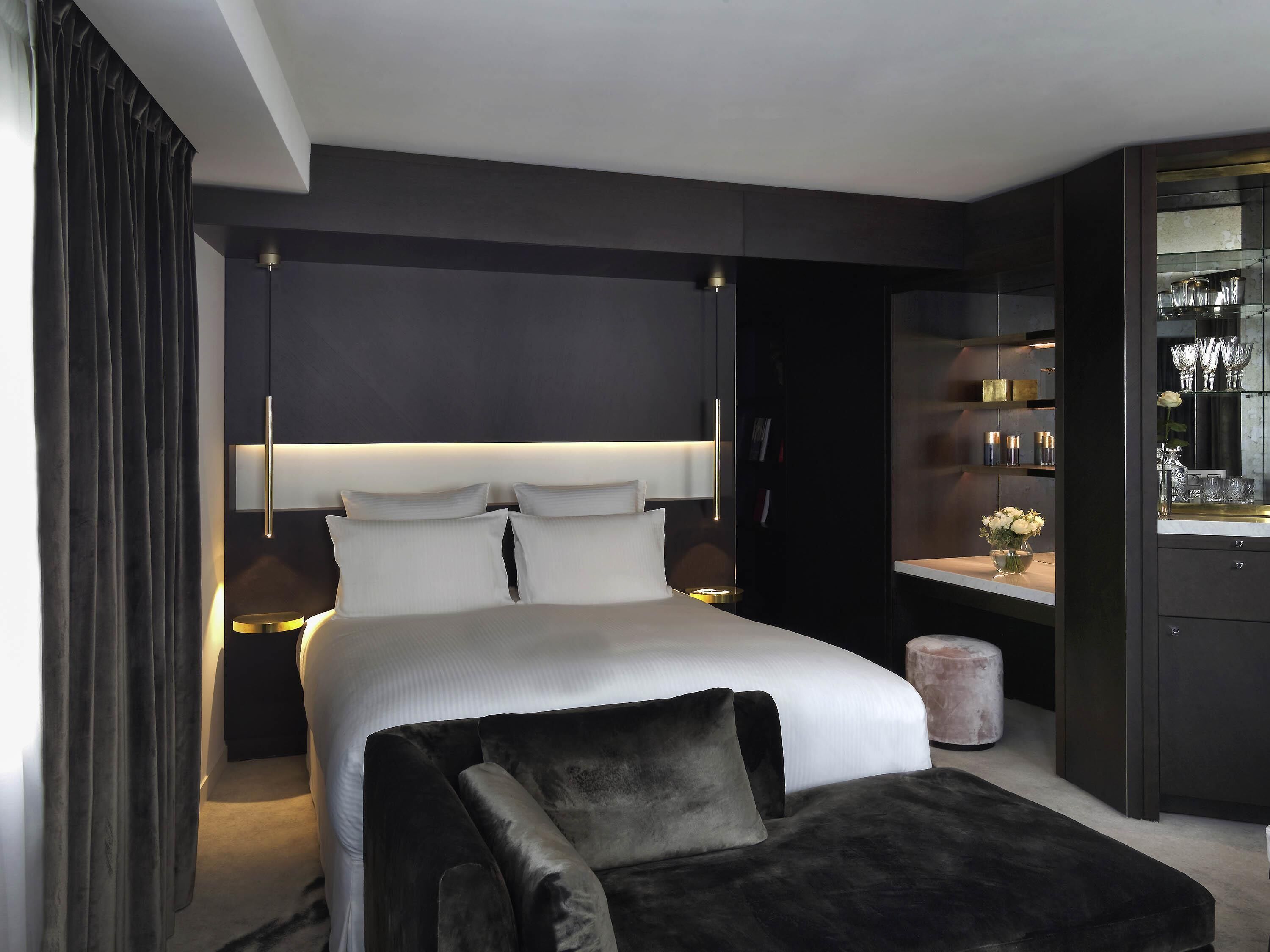 Ein modernes Schlafzimmer mit einem großen Bett, Nachttischen, einem dunkelholzigen Kleiderschrank und einer Schminkkommode mit Spiegel.