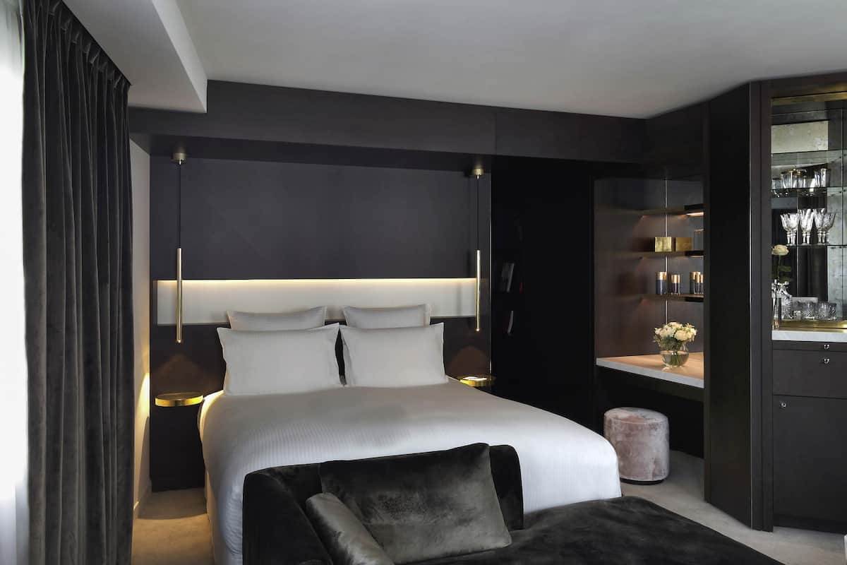 Ein modernes Schlafzimmer mit einem großen Bett, Nachttischen, einem dunkelholzigen Kleiderschrank und einer Schminkkommode mit Spiegel.