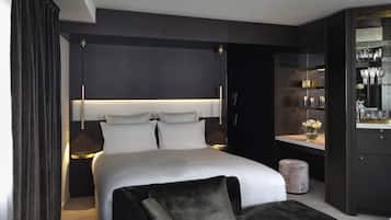 Ein modernes Schlafzimmer mit einem großen Bett, Nachttischen, einem dunkelholzigen Kleiderschrank und einer Schminkkommode mit Spiegel.