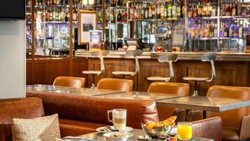 Un'area bar con diverse bottiglie di liquore, un bancone e posti a sedere.