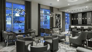 A modern hotel lobby with a seating area, large windows, and a bar. - AC Hotel by Marriott Boston North (Medford)