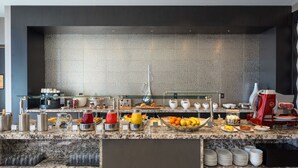 A modern breakfast buffet with a variety of food items, including fruits, pastries, and beverages, arranged on a granite countertop. - AC Hotel by Marriott Boston North (Medford)
