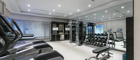 Ein modernes Fitnessstudio mit Laufbändern, Krafttrainingsgeräten und Kurzhanteln.