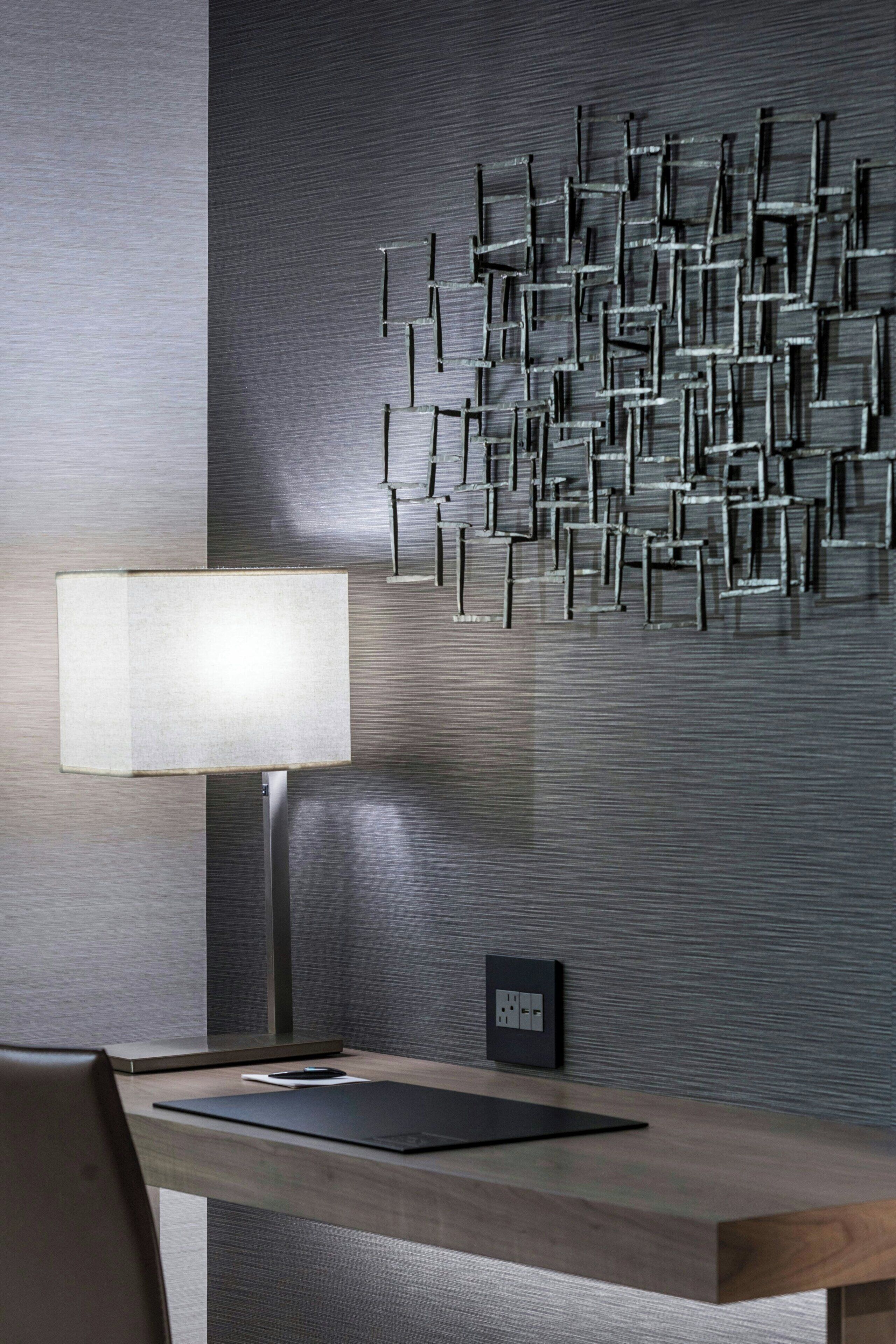 A modern room with a desk, a lamp, and a wall-mounted light fixture.