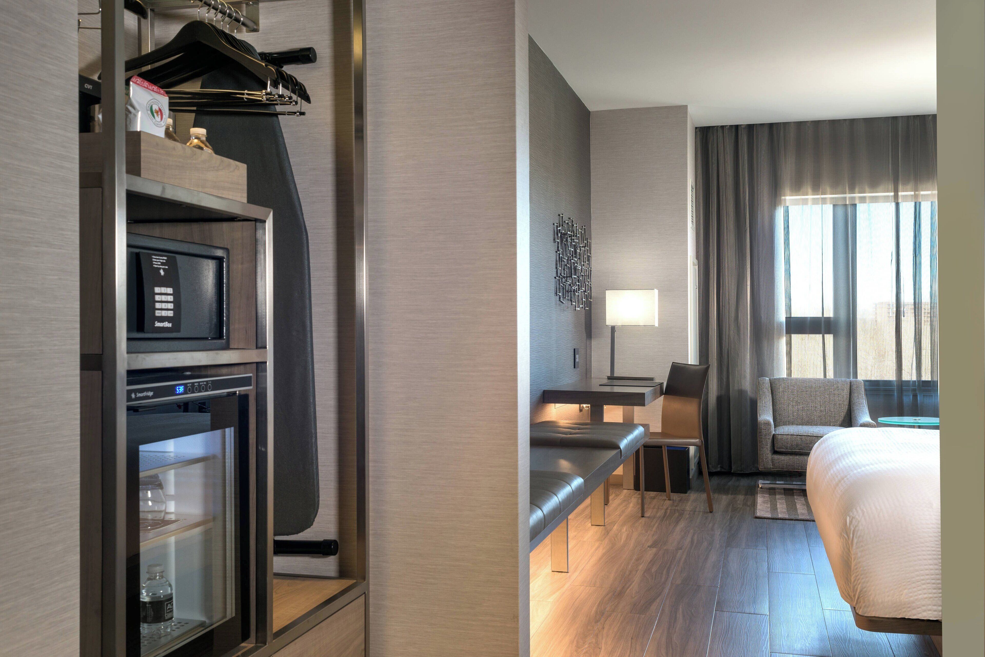 Une chambre d’hôtel équipée d’un minibar, d’un bureau avec une chaise, d’un canapé et d’un lit.