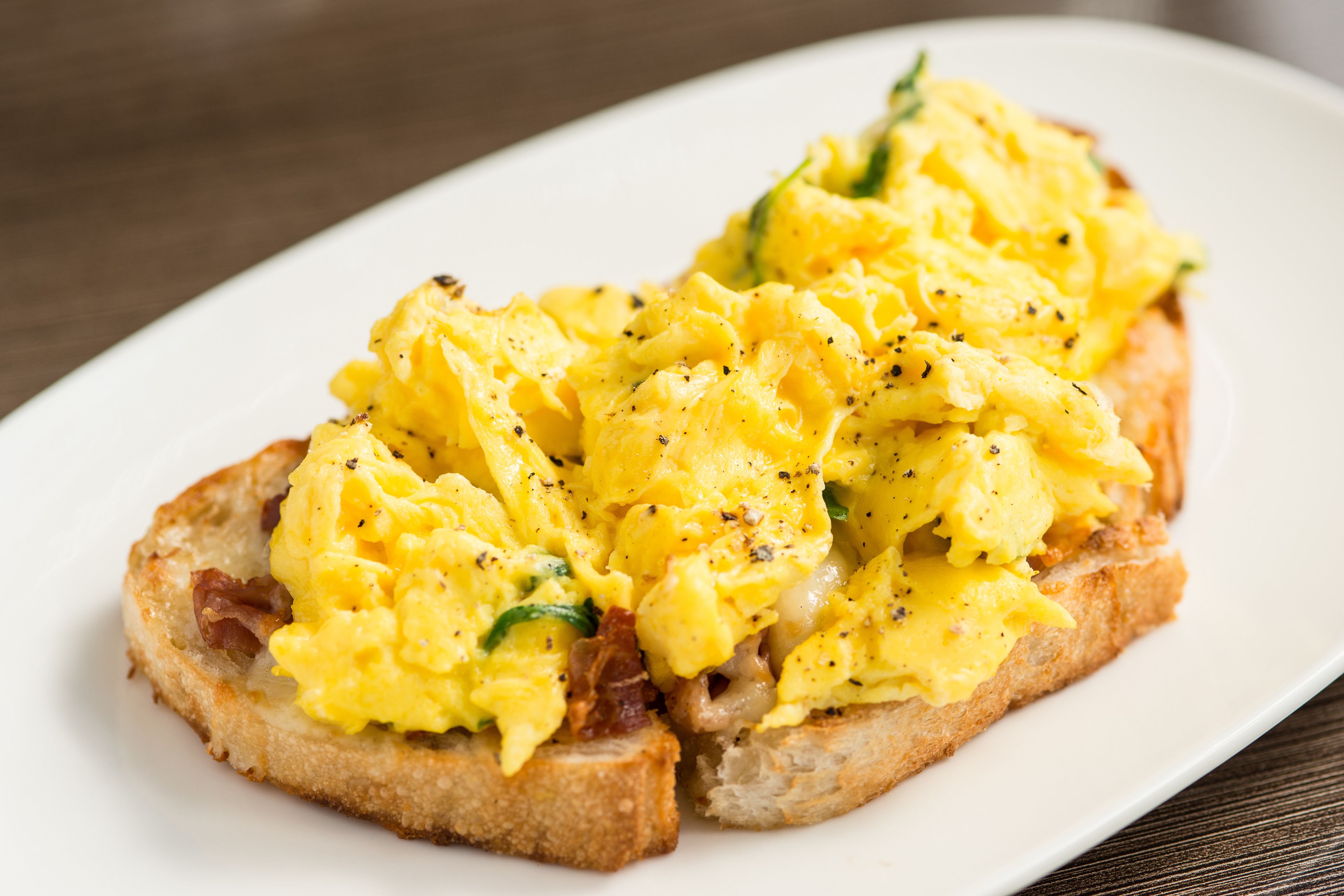 Scrambled eggs on toast with a side of bacon.