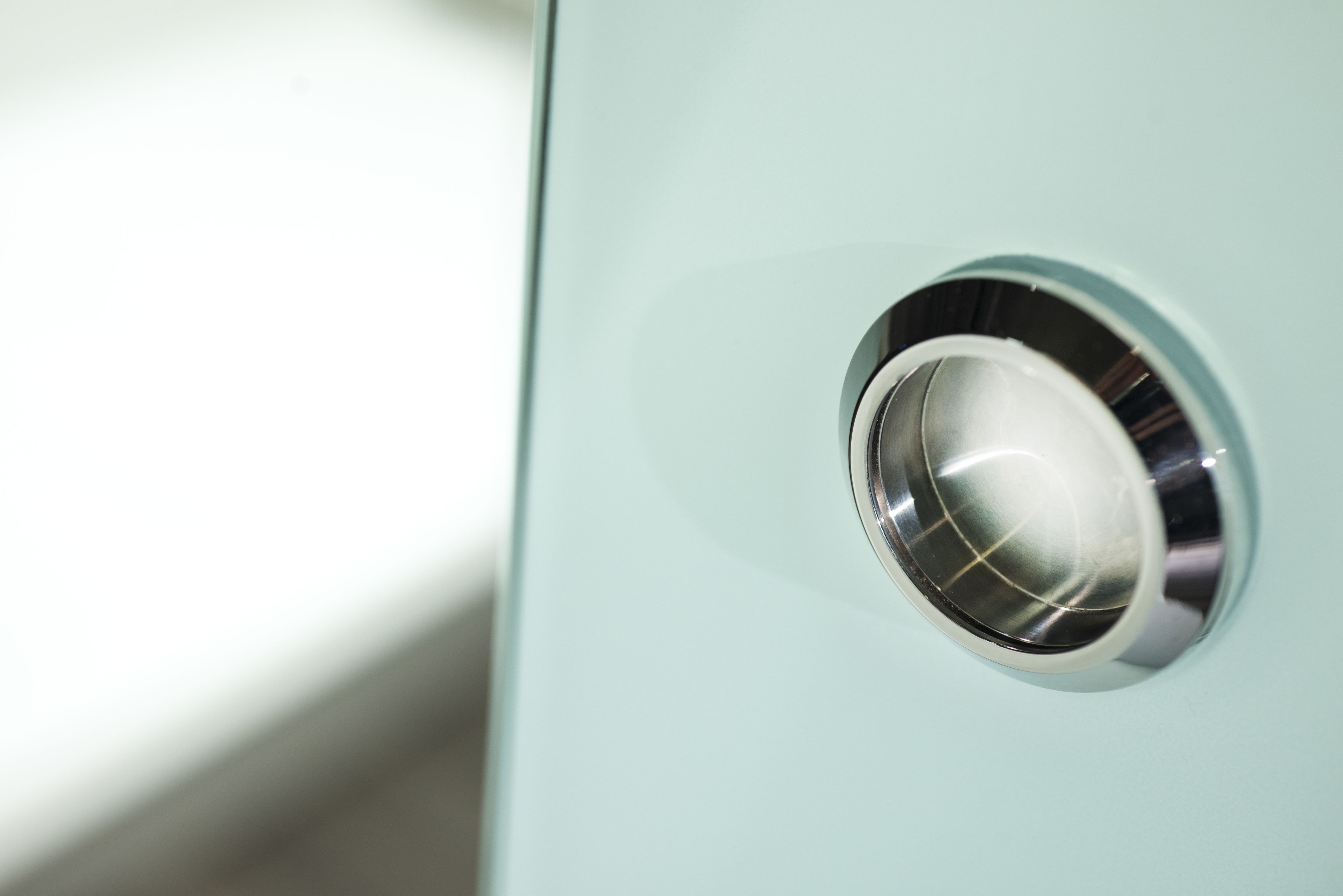 Close-up van een metalen, ronde hendel op een lichtgekleurd oppervlak.