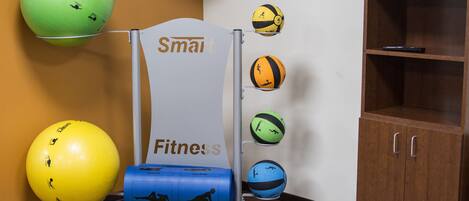 Ein Fitnessraum mit Übungsbällen, einem Smart Roller und einem Schrank.