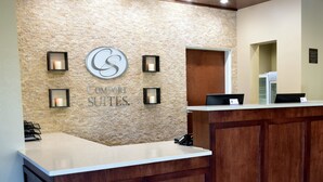 A reception desk with a stone wall backdrop, a sign reading "Comfort Suites," and four wall-mounted sconces. - Comfort Suites Dunnellon near Rainbow Springs (Dunnellon)