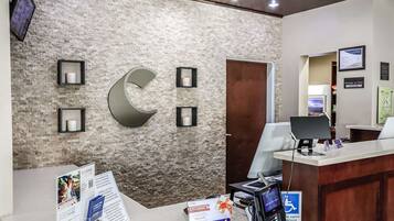 A reception area with a stone wall, a large 'C' logo, a reception desk, and informational posters.