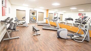 Une salle de sport équipée de tapis de course, de vélos elliptiques et de poids libres.