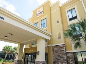 A hotel with a yellow facade, a sign reading "Comfort Suites," and a covered entrance area. - Comfort Suites Dunnellon near Rainbow Springs (Dunnellon)