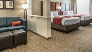 A hotel room with a sofa, two beds, a mirror, and a lamp. - Comfort Suites Dunnellon near Rainbow Springs (Dunnellon)