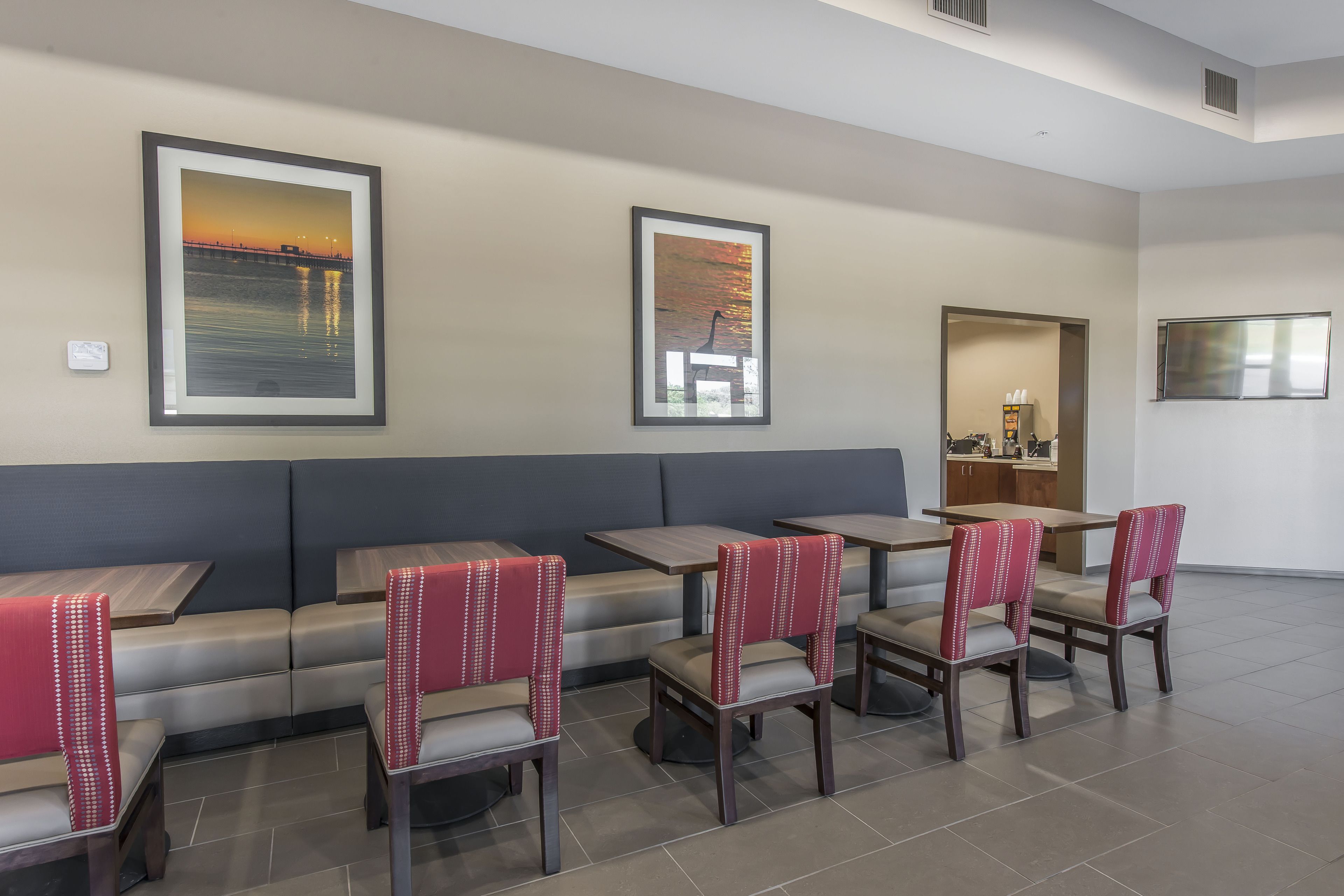 A restaurant with booths, high-top tables, and chairs. There are framed pictures on the walls.