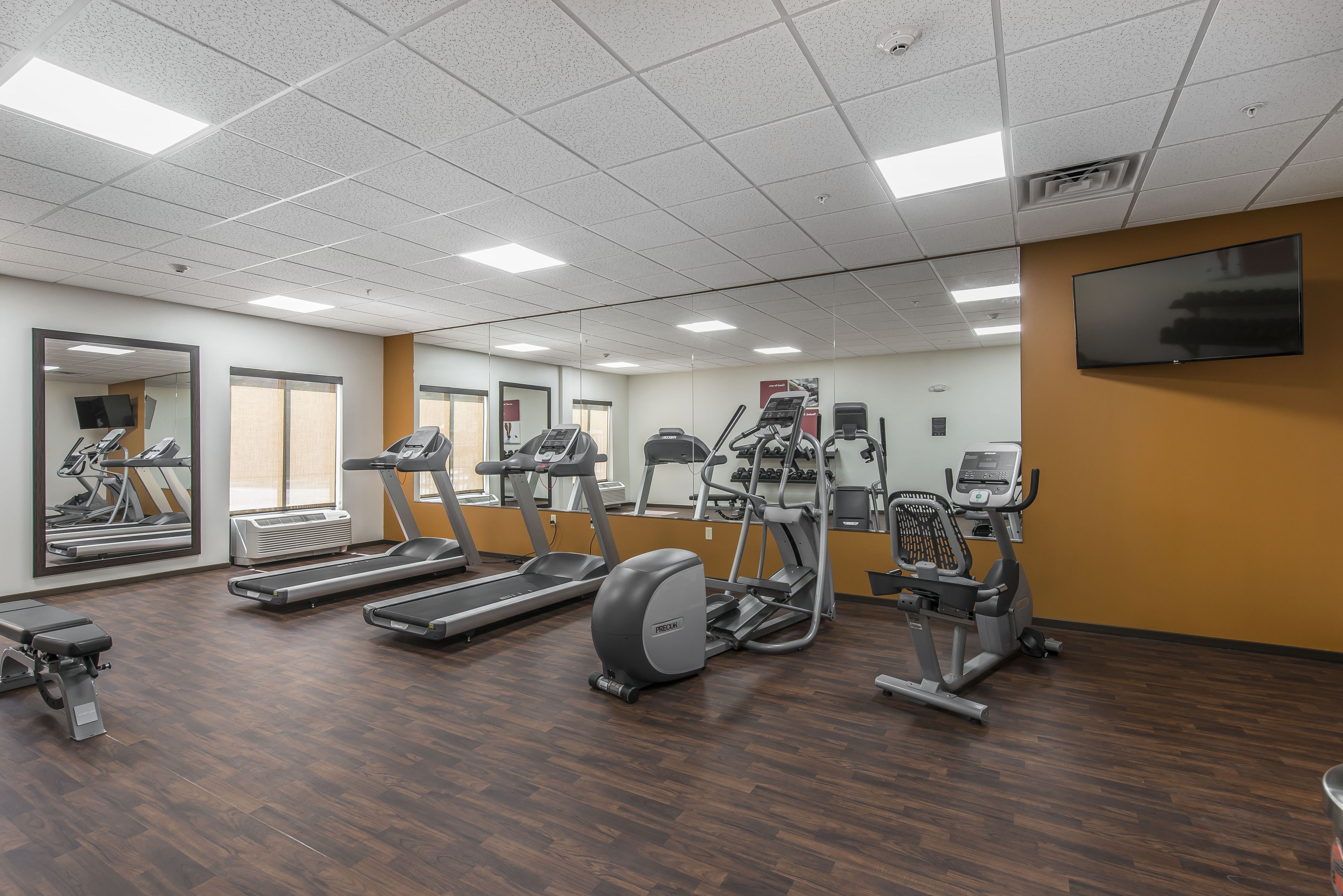 Un gimnasio con cintas de correr, elípticas y una bicicleta estática.