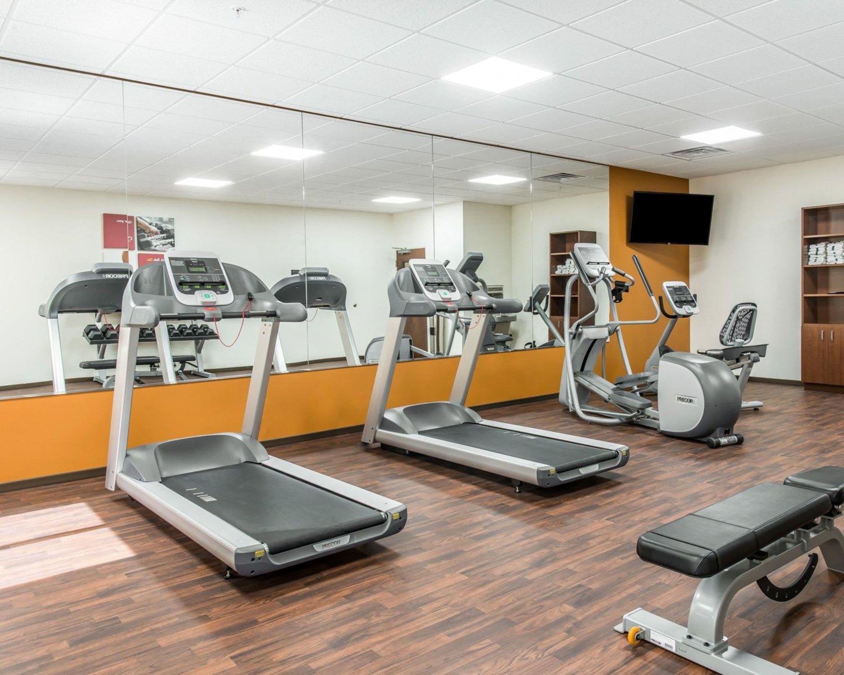 A gym with treadmills, an elliptical, and a bench.