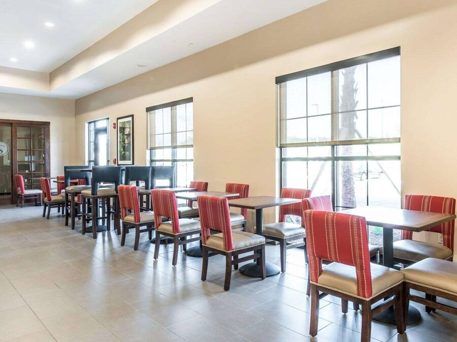 Un comedor espacioso con varias mesas y sillas, ventanas amplias que dejan entrar luz natural y un diseño de interiores moderno.