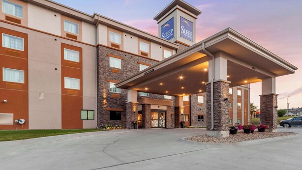Un hotel moderno con un acceso cubierto, varias ventanas y una señalización llamativa.