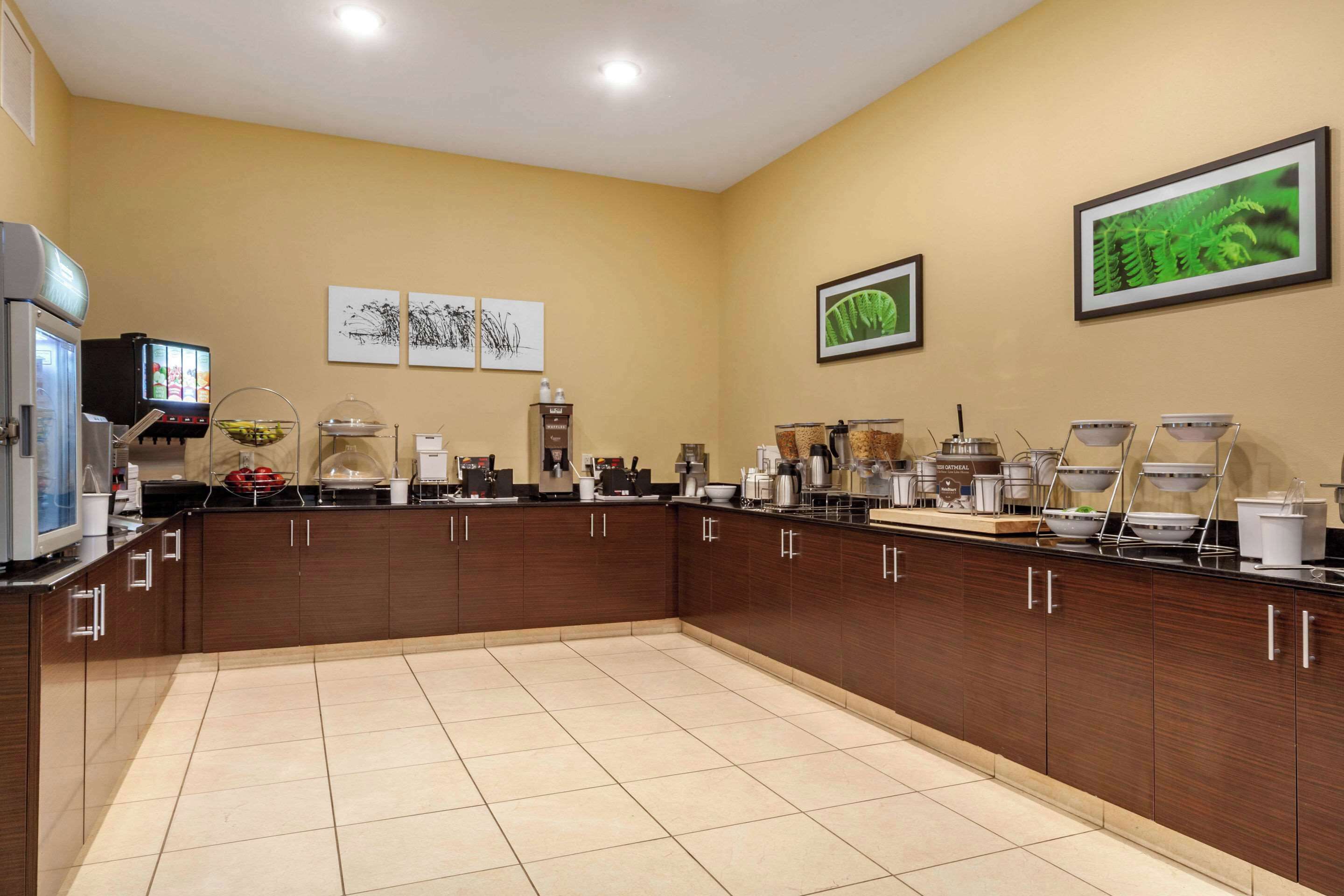 A modern kitchen with a long counter, equipped with various appliances and food dispensers.