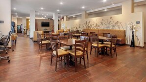 Un restaurante espacioso con varias mesas y sillas, una zona de bar y un televisor montado en la pared.