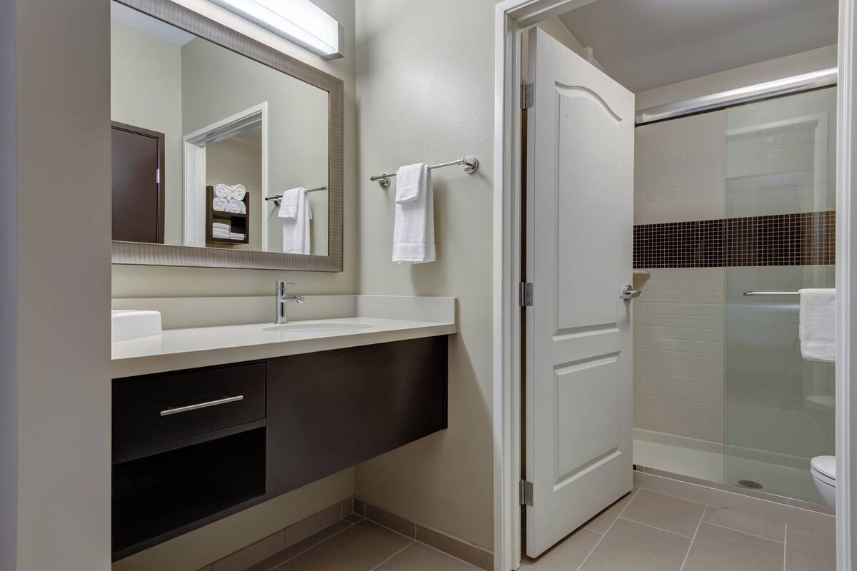Un baño moderno con tocador, espejo, toallero y cabina de ducha de vidrio.