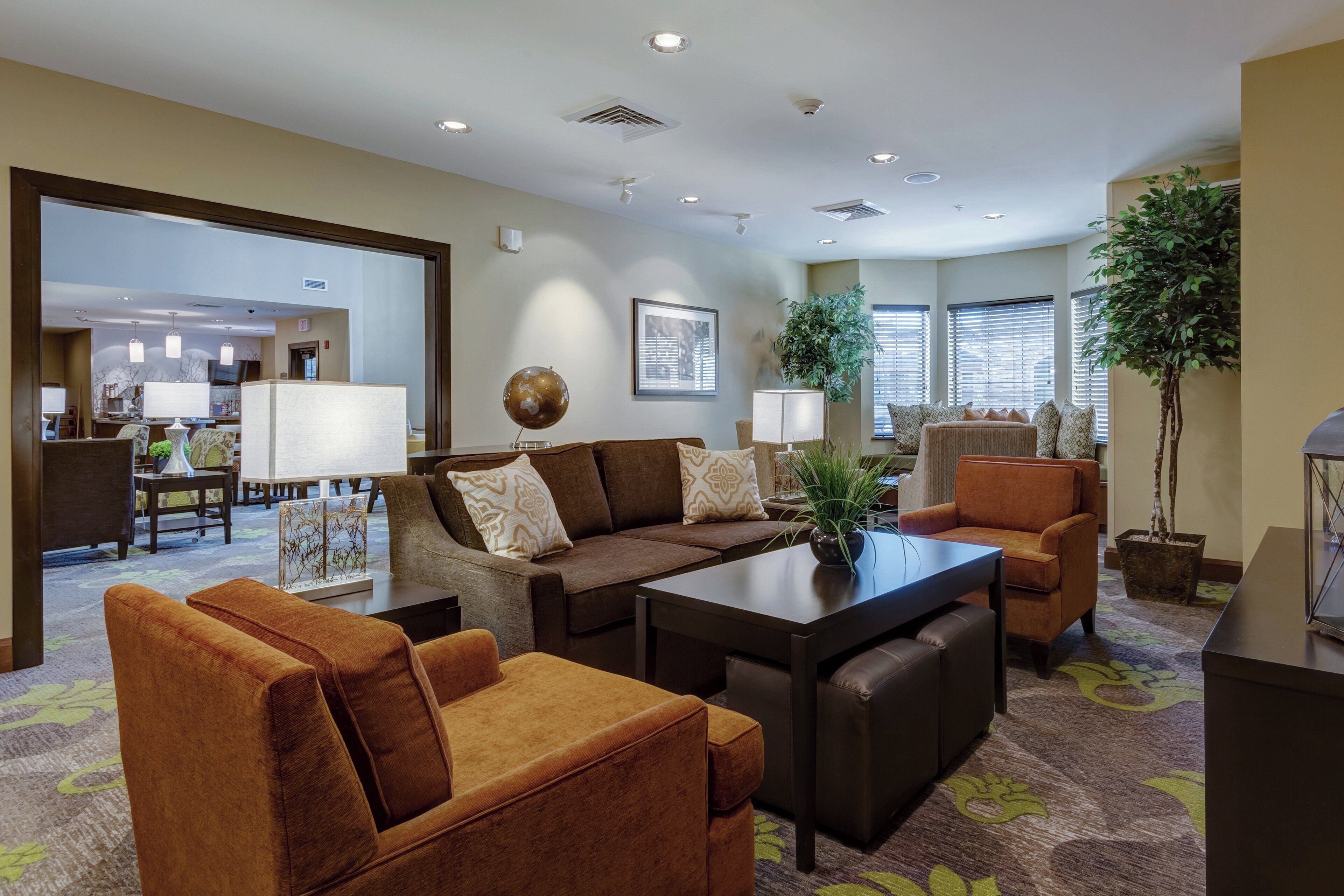 A spacious living area with a sofa set, a coffee table, and a dining table. There are potted plants and a globe on the coffee table.