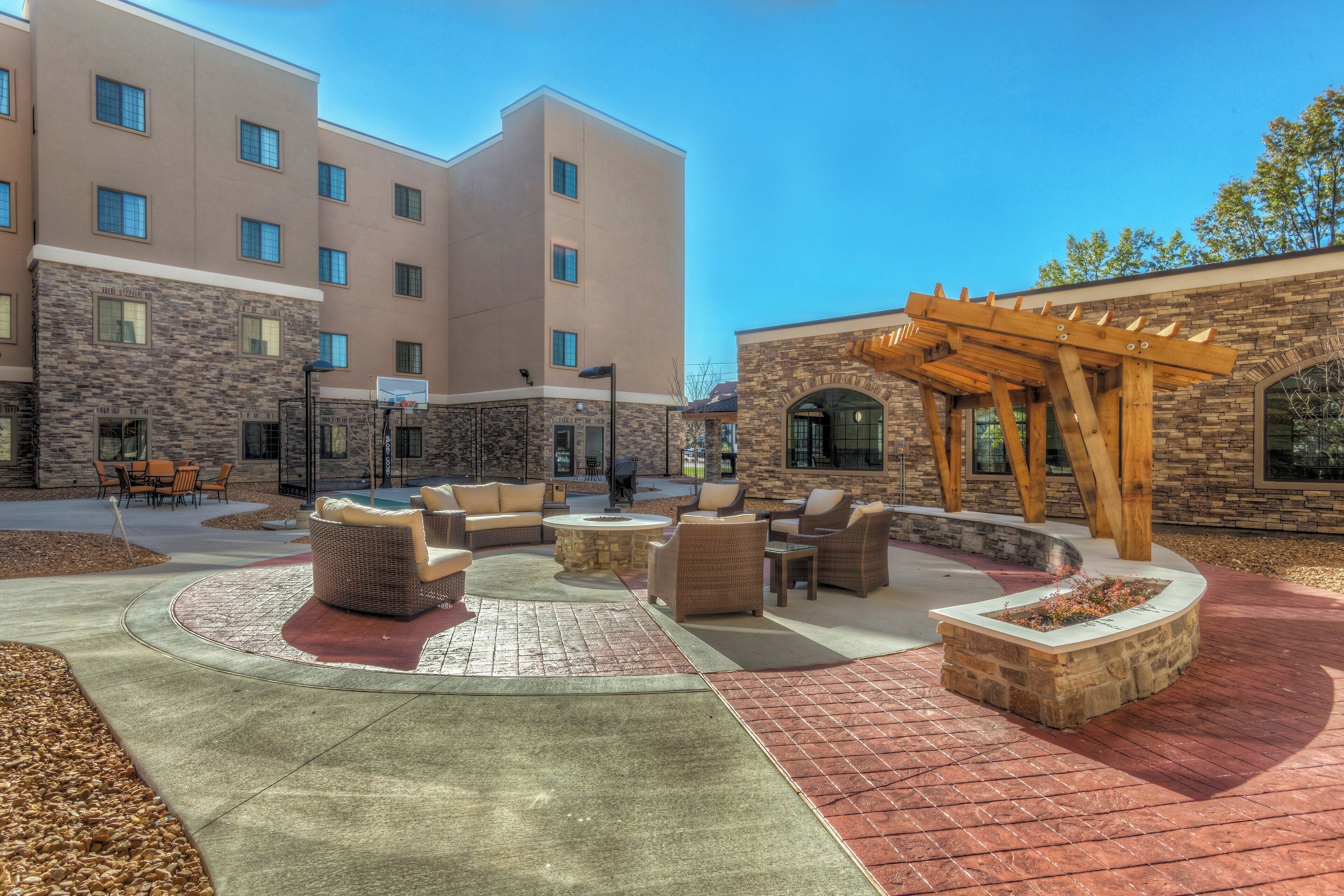 A courtyard with outdoor seating, a pergola, and a stone building with multiple windows.