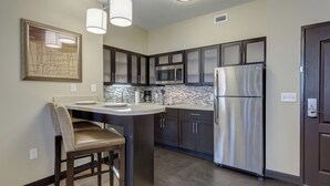 A modern kitchen with dark cabinets, stainless steel appliances, and a bar area.