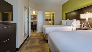 Una habitación de hotel con dos camas, televisión, escritorio y vestidor.